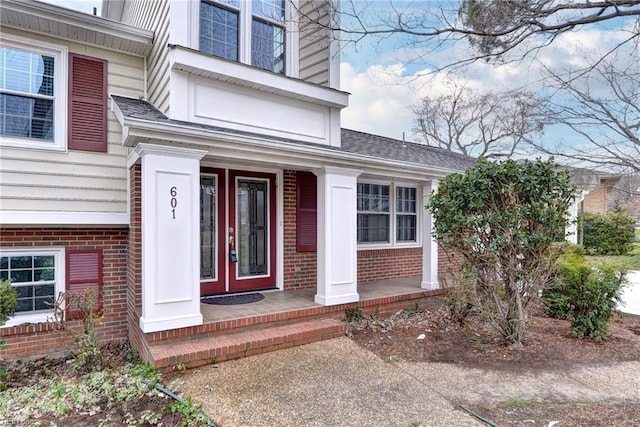 601 Windemere Rd, Newport News, VA 23602 - view of exterior entry with covered porch, a shingled roof, and brick siding