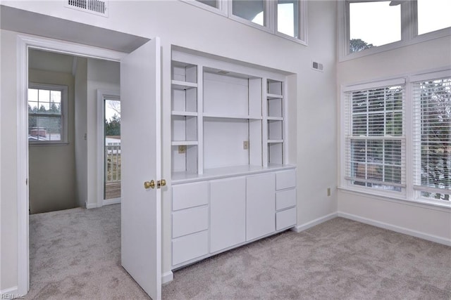 interior space with baseboards, visible vents, and light colored carpet