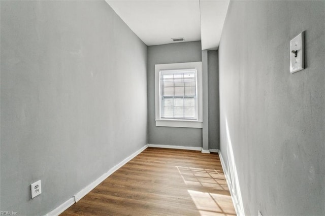 empty room featuring wood finished floors, visible vents, and baseboards