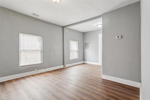 empty room with a healthy amount of sunlight, baseboards, and wood finished floors