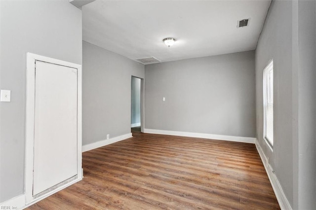 empty room with baseboards, visible vents, and wood finished floors