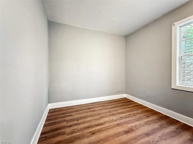 spare room featuring baseboards and wood finished floors