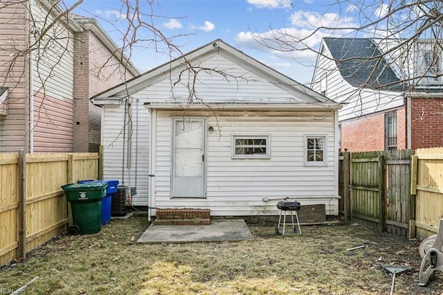 rear view of house featuring entry steps, a fenced backyard, and central AC