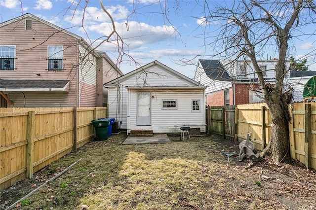 back of property with entry steps, an outdoor structure, and a fenced backyard