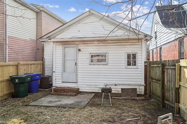 rear view of house featuring entry steps, a fenced backyard, and central air condition unit