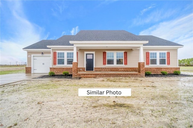 craftsman house with a shingled roof, brick siding, driveway, and a garage