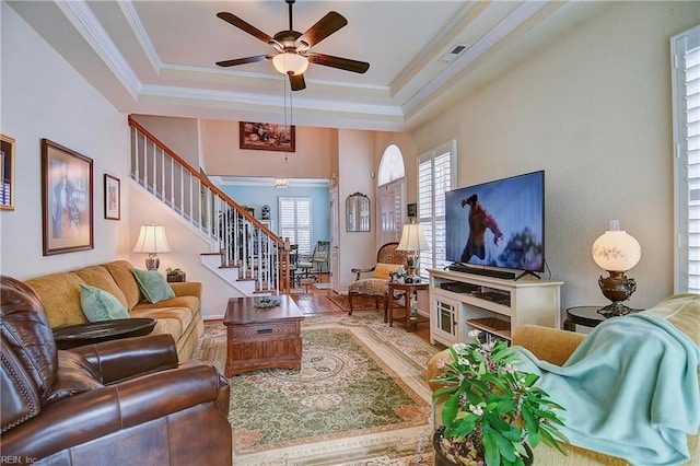 living area with visible vents, ornamental molding, a ceiling fan, wood finished floors, and stairs