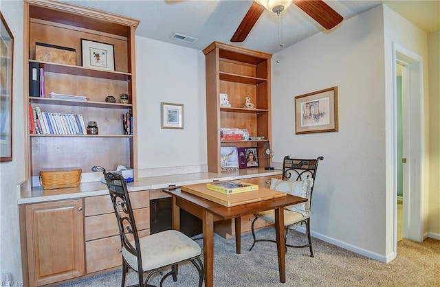 home office with a ceiling fan, light carpet, visible vents, and baseboards