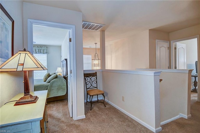 corridor featuring carpet floors, baseboards, visible vents, and an upstairs landing