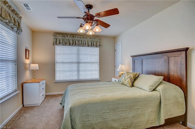 bedroom with light colored carpet, visible vents, a ceiling fan, a textured ceiling, and baseboards