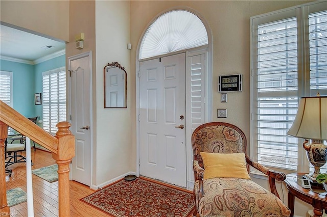 foyer with ornamental molding, visible vents, light wood-style floors, and baseboards