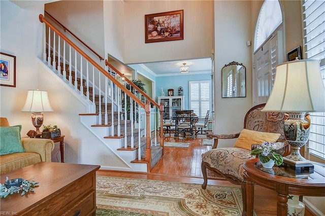 interior space with ornamental molding, wood finished floors, and a high ceiling