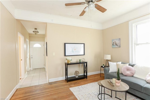 living room featuring light wood finished floors, plenty of natural light, baseboards, and a ceiling fan