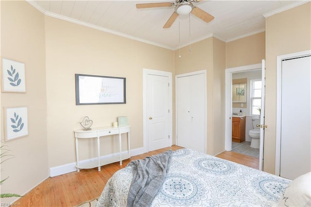 bedroom with baseboards, ornamental molding, multiple closets, and light wood-style floors