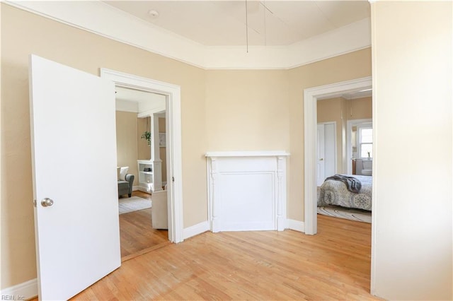 interior space with ornamental molding, light wood-style flooring, and baseboards