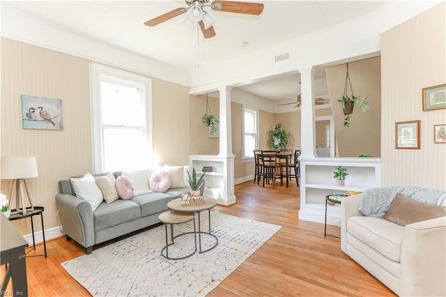 living area with visible vents, ceiling fan, light wood-style flooring, and ornate columns