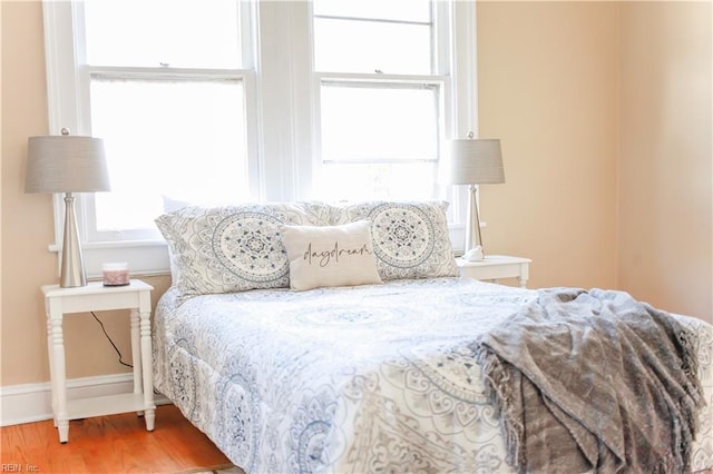 bedroom featuring multiple windows, wood finished floors, and baseboards