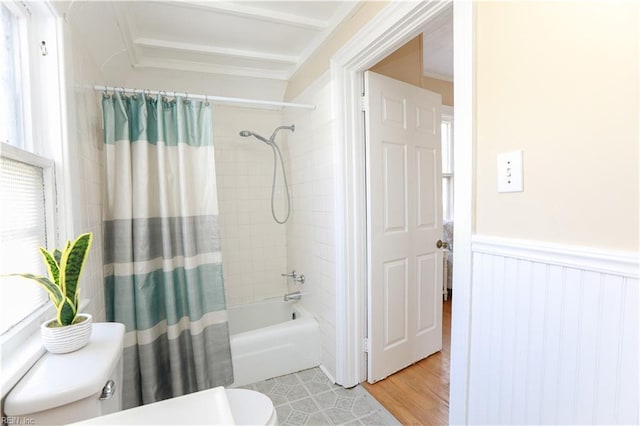 full bathroom featuring a wainscoted wall, crown molding, shower / bathtub combination with curtain, and toilet