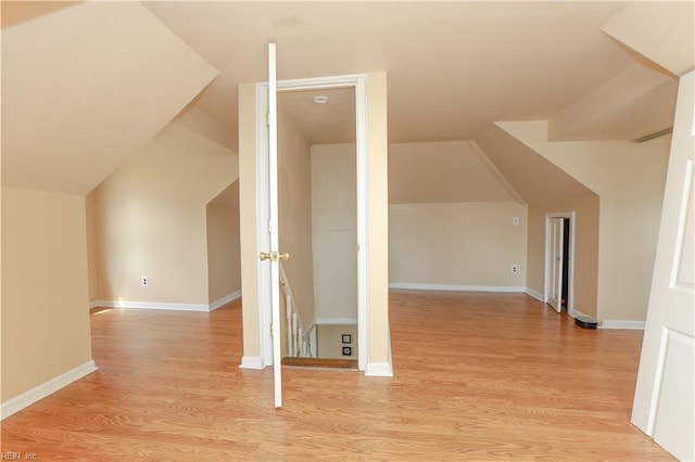 bonus room with light wood-type flooring, lofted ceiling, and baseboards