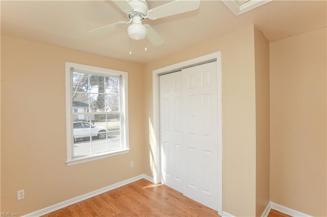 unfurnished bedroom featuring light wood-style floors, a closet, ceiling fan, and baseboards