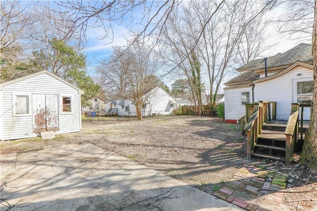 view of yard with fence, a deck, and an outdoor structure