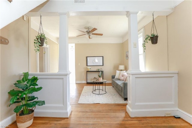 sitting room with baseboards, decorative columns, a ceiling fan, and wood finished floors