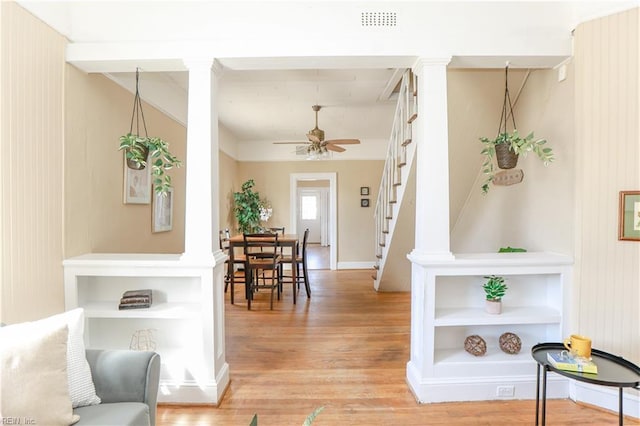 interior space with decorative columns, visible vents, stairway, a ceiling fan, and light wood-type flooring