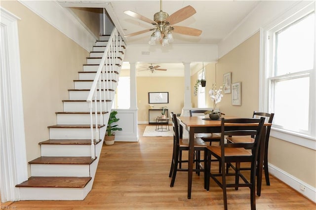 dining room with ceiling fan, light wood finished floors, baseboards, and ornate columns