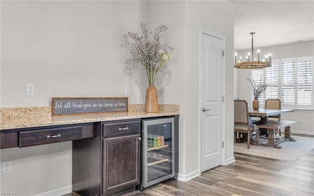 bar with baseboards, wine cooler, wood finished floors, and a notable chandelier