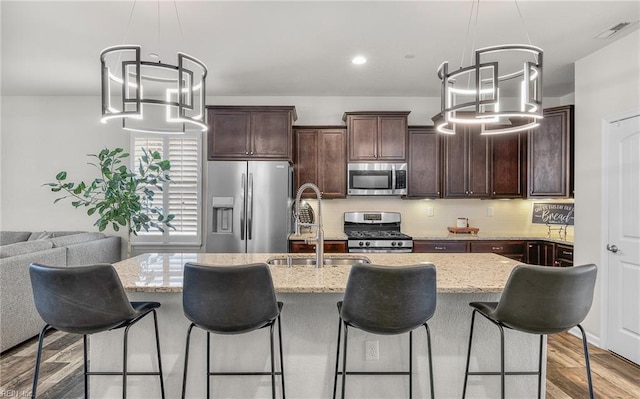 kitchen featuring visible vents, appliances with stainless steel finishes, dark brown cabinets, light wood-type flooring, and a sink