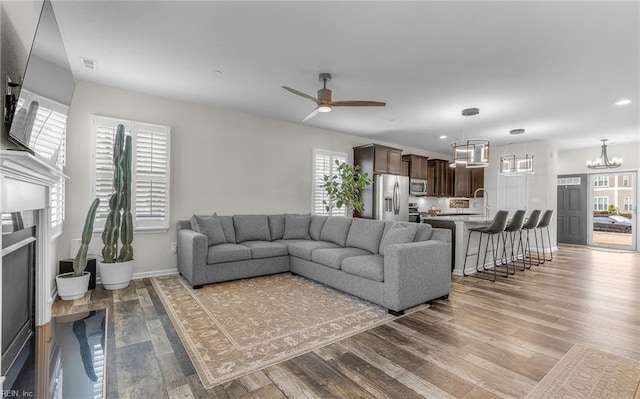 living room with ceiling fan with notable chandelier, a healthy amount of sunlight, and wood finished floors