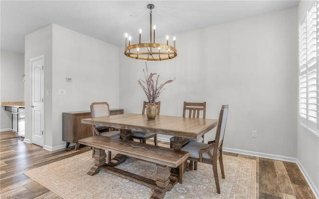 dining space featuring baseboards, a chandelier, and wood finished floors