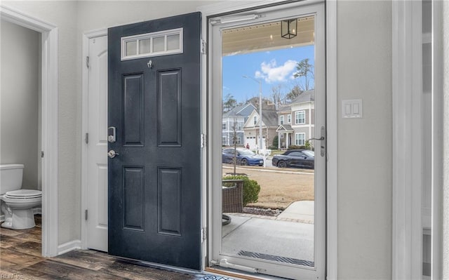 foyer entrance with a textured wall, dark wood-style flooring, and a residential view