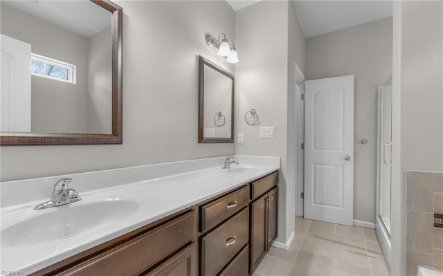 full bathroom featuring double vanity, a stall shower, a sink, and tile patterned floors