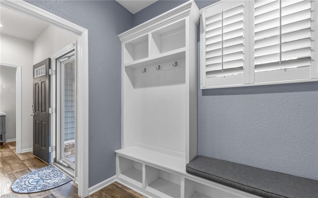 mudroom featuring baseboards, wood finished floors, and a textured wall