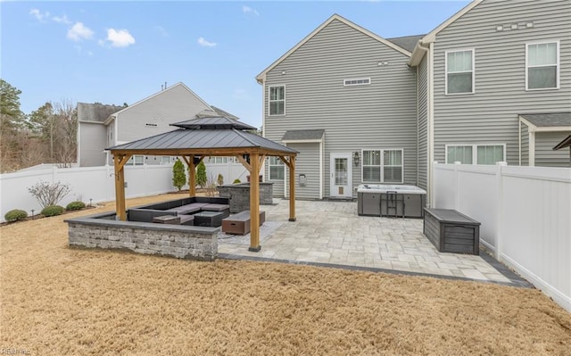 exterior space featuring a patio, a gazebo, an outdoor fire pit, a fenced backyard, and a jacuzzi