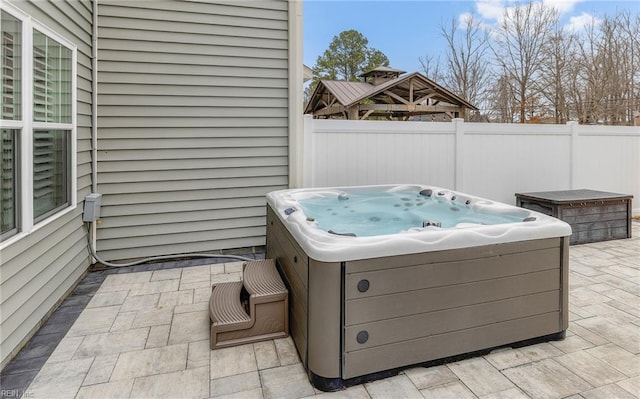 view of patio with a hot tub and fence