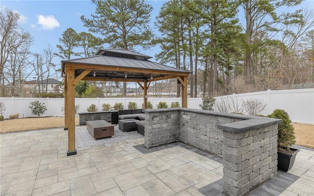 view of patio featuring a gazebo, a fenced backyard, and an outdoor living space with a fire pit