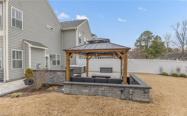 view of patio / terrace with an outdoor living space with a fire pit, a hot tub, fence, and a gazebo