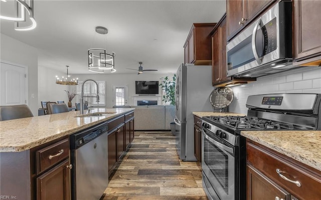 kitchen with decorative backsplash, open floor plan, dark wood-type flooring, stainless steel appliances, and a sink