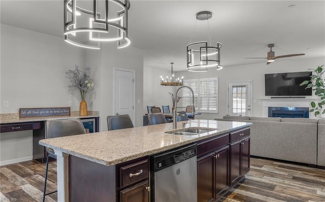 kitchen with stainless steel dishwasher, dark wood-style flooring, a fireplace, and a sink