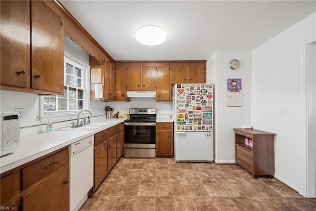 kitchen with white appliances, brown cabinetry, a sink, and under cabinet range hood