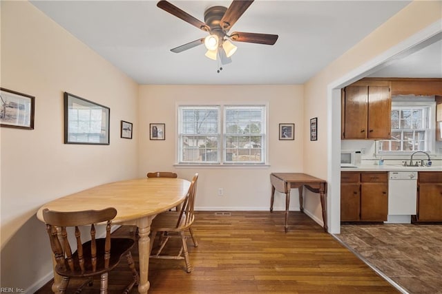 dining space featuring baseboards, dark wood-style flooring, a ceiling fan, and a healthy amount of sunlight