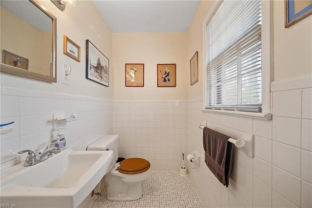 bathroom with wainscoting, a sink, toilet, and tile patterned floors