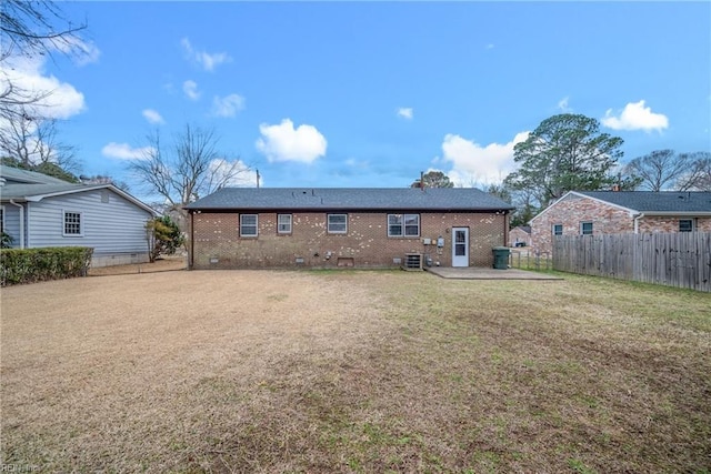 rear view of house with a patio, brick siding, a lawn, and fence