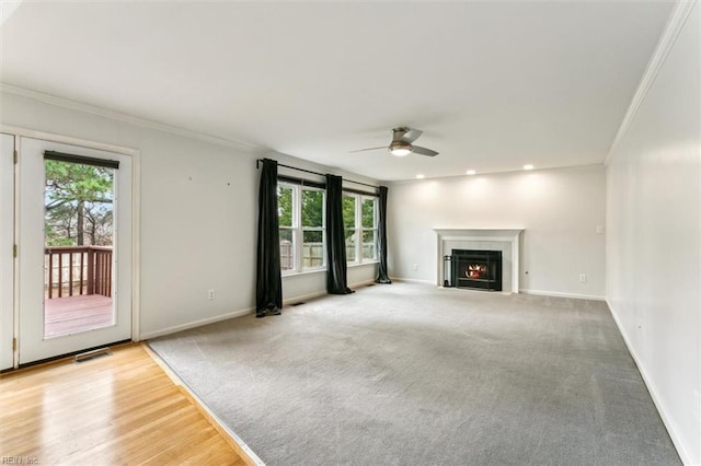 unfurnished living room with a fireplace with flush hearth, ornamental molding, and baseboards