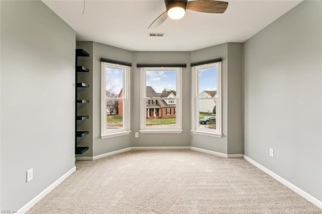 unfurnished room with carpet floors, visible vents, ceiling fan, and baseboards