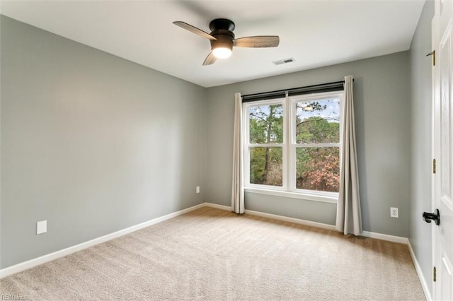 spare room with a ceiling fan, visible vents, light carpet, and baseboards