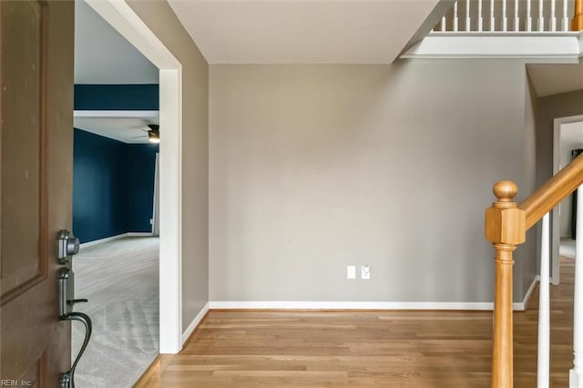 interior space featuring a ceiling fan, stairs, baseboards, and wood finished floors