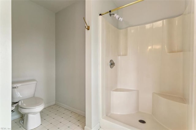 bathroom featuring toilet, baseboards, and a shower